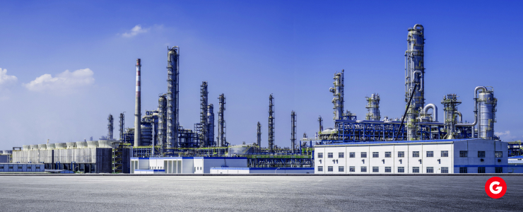 A large industrial refinery featuring numerous pipes and tanks against a clear sky.