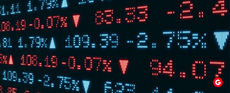 Stock market trading screen illuminated by red and blue lights, displaying various financial data and trends.