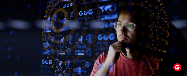 A man wearing glasses intently observes a computer screen, focused on the content displayed.