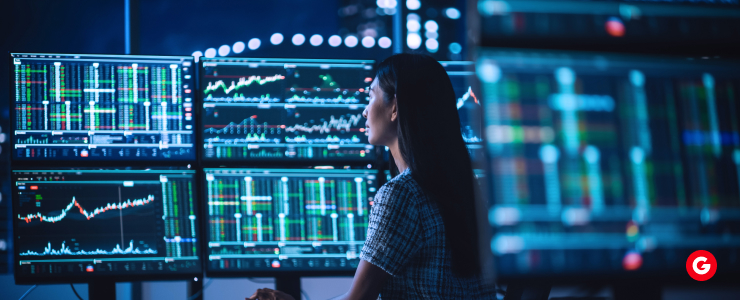 A woman focused on her work, seated in front of multiple computer screens displaying various data and applications.